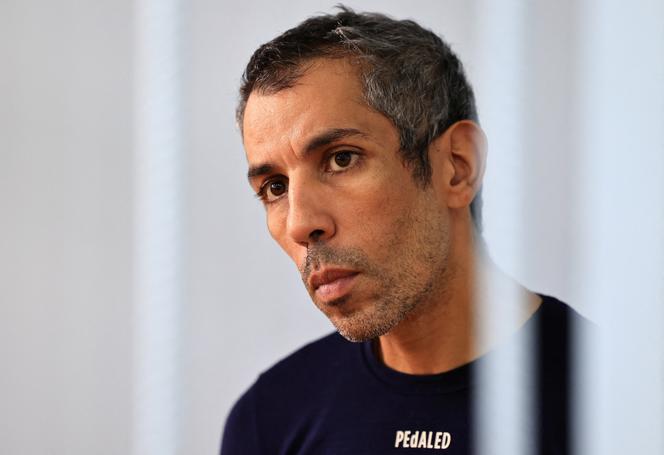 French cyclist Sofiane Sehili looks through bars of an enclosure for defendants before a court hearing in the far eastern settlement of Pogranichniy, Russia, October 23, 2025.
