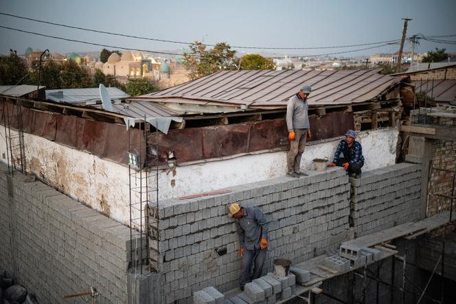 Des ouvriers du bâtiment construisent un hôtel dans la mahalla près de la mosquée Bibi-Khanym, avec le mausolée Shahi-Zinda visible en arrière-plan, Samarcande, Ouzbékistan, 2025.