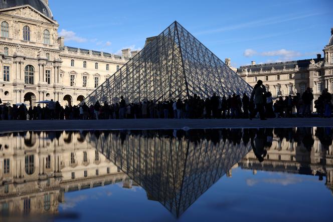 Des personnes se tiennent devant le Louvre, après l’interpellation par la police française de suspects dans l’affaire du vol dont a été victime le musée, à Paris, le 26 octobre 2025.