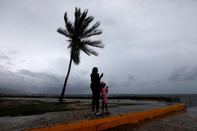 A woman and a child stand along the Kingston waterfront as Hurricane Melissa approaches, in Kingston, Jamaica, on October 27, 2025. 
