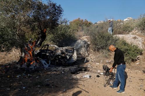 Pessoas inspecionam um veículo queimado no local onde as forças israelenses mataram três palestinos, perto de Jenin, na Cisjordânia, em 28 de outubro de 2025.