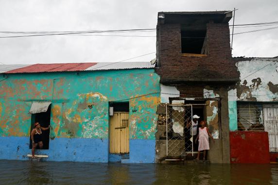 Des habitants se tiennent devant leurs maisons dans une rue inondée après le passage de l’ouragan Melissa, à Santiago de Cuba, le 29 octobre 2025. 