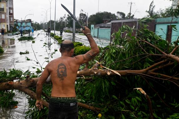 Un homme coupe les branches d’un arbre abattu par les vents violents, après le passage de l’ouragan Melissa, à Santiago de Cuba, le 29 octobre 2025. 