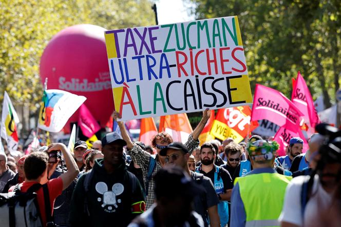 Un manifestant brandit une pancarte « Taxe Zucman, ultra-riches à la caisse » lors d’une manifestation, à Paris, 18 septembre 2025.