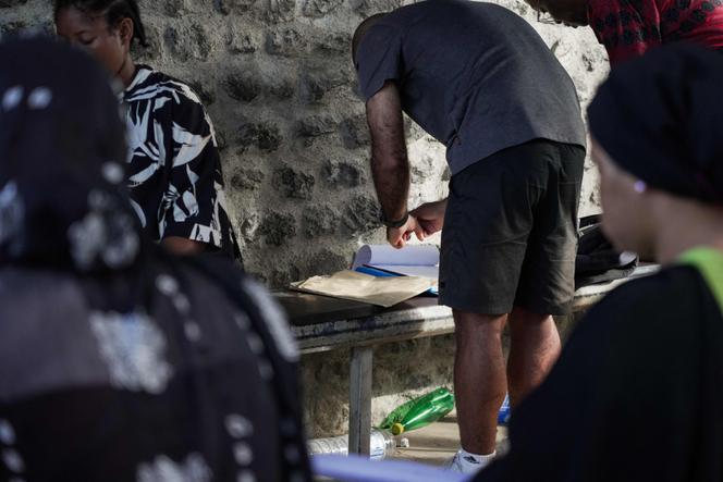 Un agent associatif lit des documents apportés par des proches de personnes détenues près du centre de rétention administrative de Pamandzi, à Mayotte, le 29 octobre 2025.