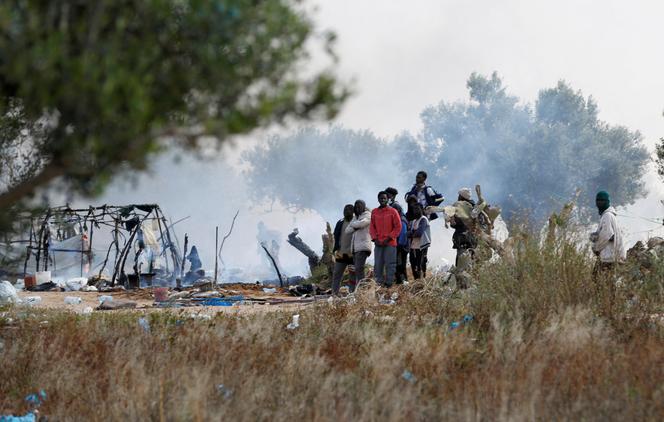Des migrants rassemblés près de tentes incendiées, après le démantèlement d’un camp par les autorités à Sfax, en Tunisie, le 24 avril 2025. 