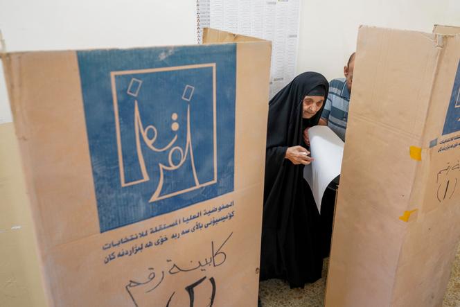 An Iraqi woman votes at a voting booth in legislative elections, in Najaf, Iraq, November 11, 2025.