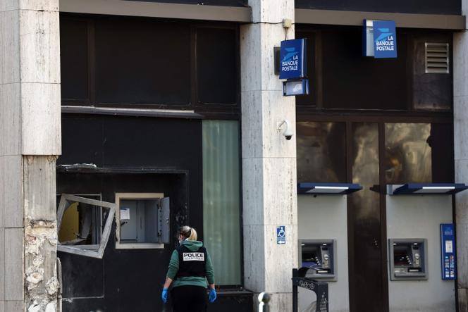 Une policière scientifique inspecte la façade du bureau de poste braqué à l’explosif à Roubaix, le 12 novembre 2025. 