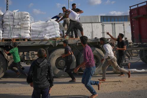 Des Palestiniens s’emparent de sacs de farine, sur un camion transportant de l’aide du Programme alimentaire mondial, à Deir el-Balah, dans le centre de Gaza, le 15 novembre 2025.