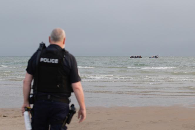 Un policier observe une embarcation de migrants se faisant approcher par un bateau de la gendarmerie maritime, sur la plage de Gravelines (Nord), le 2 juillet 2025.