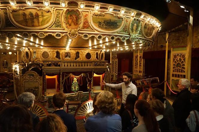 Guided tour in front of the velocipede carousel at the Museum of Fairground Arts, in Paris.