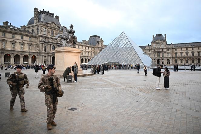 Des soldats patrouillent, lundi 20 octobre, tandis que des personnes font la queue pour tenter d’entrer au Musée du Louvre, après le vol de bijoux le 19 octobre, à Paris.