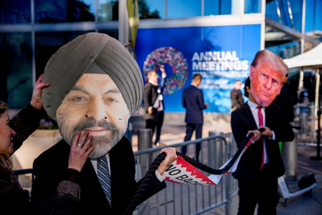Des militants écologistes, déguisés en Ajay Banga (à gauche), président de la Banque mondiale, et en Donald Trump (à droite), devant le siège du Fonds monétaire international et du Groupe de la Banque mondiale, où se tient la réunion annuelle, à Washington, le 16 octobre 2025.