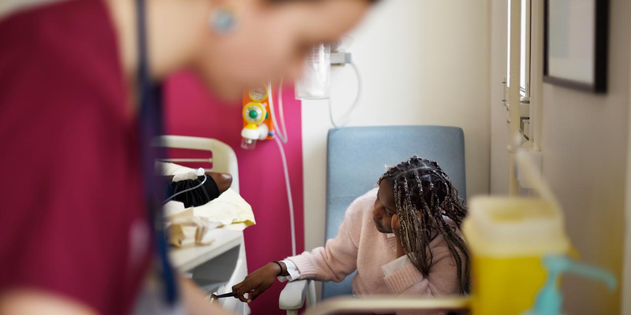 La soeur jumelle de Yohanélie, Chloé, est au côté de son frère pendant sa transfusion. Reportage sur la drépanocytose, maladie génétique héréditaire touchant les globules rouges. Service pédiatrie, Hopital Necker, Paris, France, 18 novembre 2025.