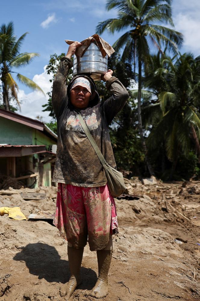 La rescapée Helen Simare-mare, 48 ans, transportant un seau de riz cuit distribué par les services d’urgence, après avoir perdu sa maison à la suite des crues éclair meurtrières qui ont frappé Sumatra, à Batang Toru (Indonésie), le 6 décembre 2025. 