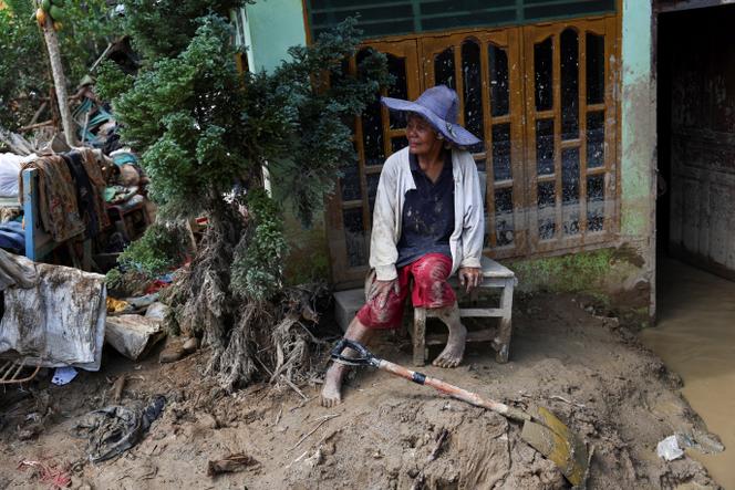 La rescapée Rismawati Simanjuntak, 63 ans, fait une pause en plein nettoyage de sa maison, abîmée par les crues éclair meurtrières qui ont frappé Sumatra, à Batang Toru (Indonésie), le 6 décembre 2025. 