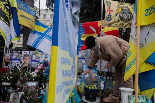 Une femme touche le portrait de son mari, mort au front, devant le mémorial installé sur la place de l’Indépendance, à Kiev, le 9 décembre 2025.