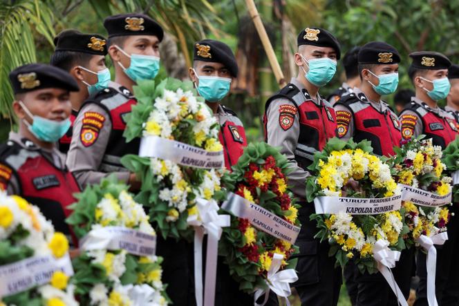 Des membres de la police portent des couronnes destinées à être déposées sur les tombes des victimes non identifiées des récentes inondations et glissements de terrain, lors d’un enterrement collectif à Padang, dans la province de Sumatra occidental, en Indonésie, le 10&nbsp;décembre 2025. 