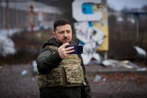 Le président ukrainien, Volodymyr Zelensky, enregistre un message vidéo sur son téléphone portable devant le panneau indiquant l’entrée de Koupiansk, dans l’oblast de Kharkiv, le 12 décembre 2025.