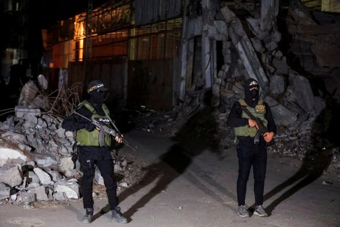 Des militants du Hamas montent la garde tandis que des véhicules de la Croix-Rouge transportent les corps d’otages remis à Israël dans le cadre de l’accord de cessez-le-feu, le 15 octobre 2025.