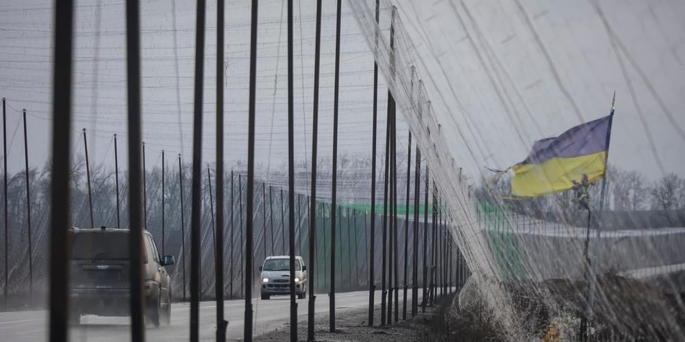 Des voitures circulent sur une route recouverte d’un filet antidrone, près de la ville d’Izum, dans la région de Kharkiv, en Ukraine, le 12 décembre 2025. - VYACHESLAV MADIYEVSKYY / REUTERS