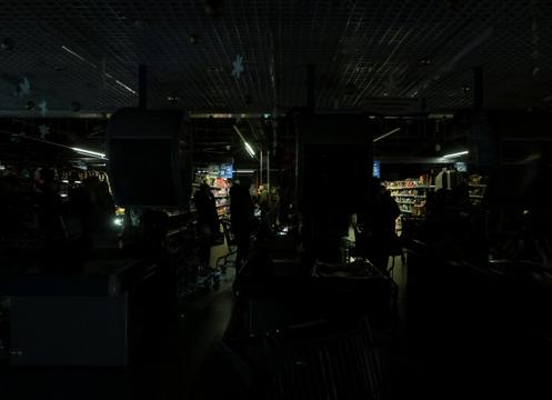 Des Ukrainiens font leurs courses dans un supermarché privé d’électricité, à Odessa, en Ukraine, le 13 décembre 2025.