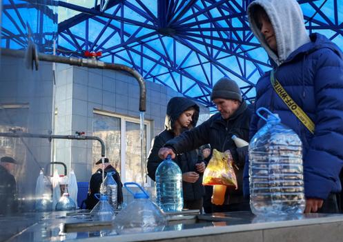 Des Odessites remplissent des bouteilles d’eau potable après l’attaque russe sur Odessa, le 13 décembre 2025.