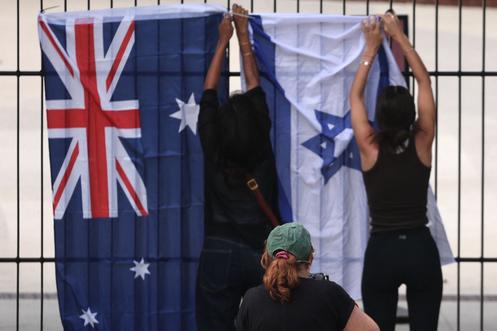 Des femmes accrochent le drapeau israélien à côté du drapeau australien au pavillon de Bondi, à Sydney, le 15 décembre 2025.