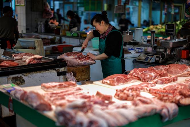 Une vendeuse découpe du porc en attendant ses clients sur un marché de Hangzhou, dans la province du Zhejiang (est de la Chine), le 10 avril 2025.