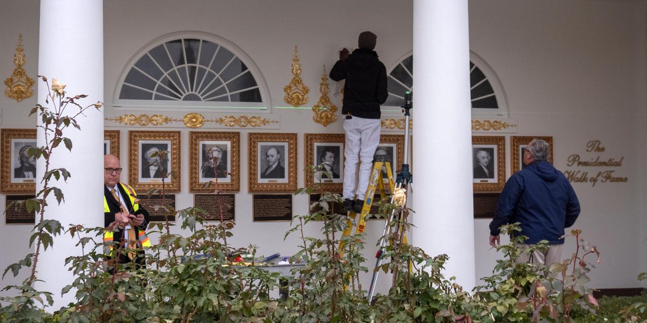 Workers use a laser level to install decorative elements on the Presidential Walk of Fame on the Colonnade of the White House, Wednesday, Dec. 17, 2025, in Washington. (AP Photo/Mark Schiefelbein)