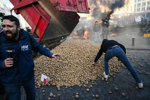 Des manifestants s’emparent de pommes de terre près du Parlement européen, lors d’une manifestation d’agriculteurs à Bruxelles, le 18 décembre 2025.
