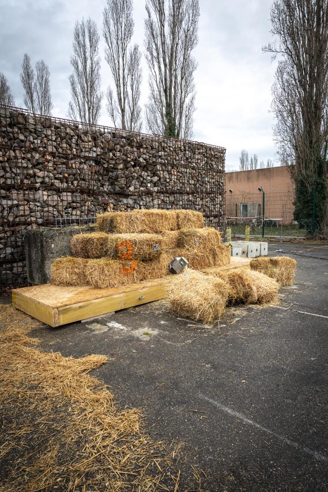 Boulet en ciment de 45&nbsp;kilos catapulté contre deux rangées de bottes de paille. Ces essais sont réalisés dans le cadre d’étude de dispositif de protection d’urgence temporaire lors d’éboulement rocheux, à&nbsp;Bron (Rhône), le 16&nbsp;décembre 2025.