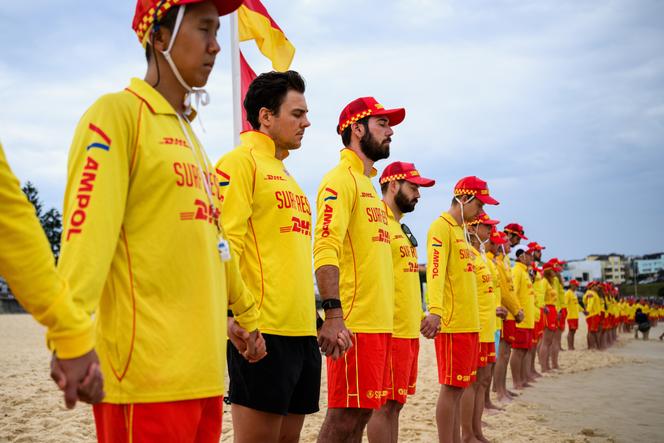 Lifeguards link hands as they line the shoreline to observe three minutes of silence to pay their respects to the victims of last Sunday's shootings at Bondi Beach in Sydney, December 20, 2025. (Bianca De Marchi/AAP Image via AP)