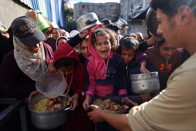 Des Palestiniens se pressent autour de plats préparés par une cuisine caritative du camp de réfugiés de Nousseirat, dans le centre de la bande de Gaza, le&nbsp;20&nbsp;décembre&nbsp;2025. 