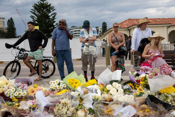 Des personnes se recueillent devant des fleurs déposés en hommage aux victimes et aux survivants de l’attentat du 14 décembre sur la plage de Bondi, à Sydney, dimanche 21 décembre 2025.