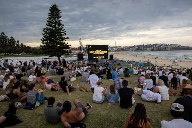 Des personnes attendent la veillée « Light Over Darkness » (La lumière sur les ténèbres) lors d’une journée nationale de deuil pour les victimes et les survivants de la fusillade meurtrière survenue lors de la fête juive de Hanoukka sur la plage de Bondi le 14 décembre à Sydney (Australie), dimanche 21 décembre 2025.