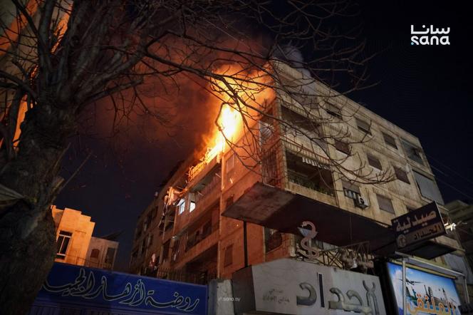 This photo released by the official Syrian news agency SANA shows flames rising from a building after clashes broke out between security forces and Kurdish fighters in neighborhoods of the northern Syrian city of Aleppo, December 22, 2025. 