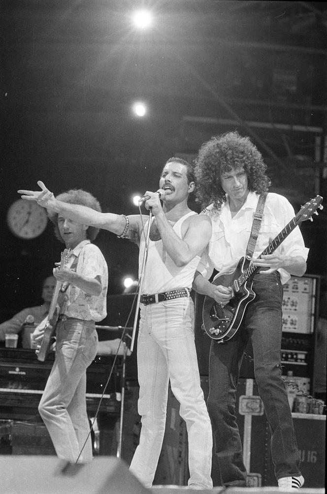 Freddie Mercury (au centre), Brian May (à droite) et John Deacon, du groupe Queen, en concert à Londres le 13 juillet 1985.