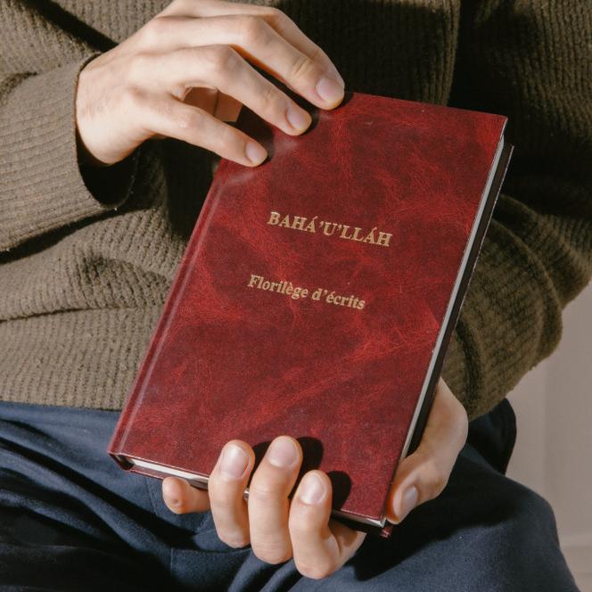 Romain tient le livre qui est au centre de sa spiritualité. « Il m’inspire, parce qu’on peut méditer longtemps sur ces écritures, pour essayer de comprendre toutes leurs dimensions. » Chez lui, dans le 12ᵉ arrondissement de Paris, le 19 novembre 2025.