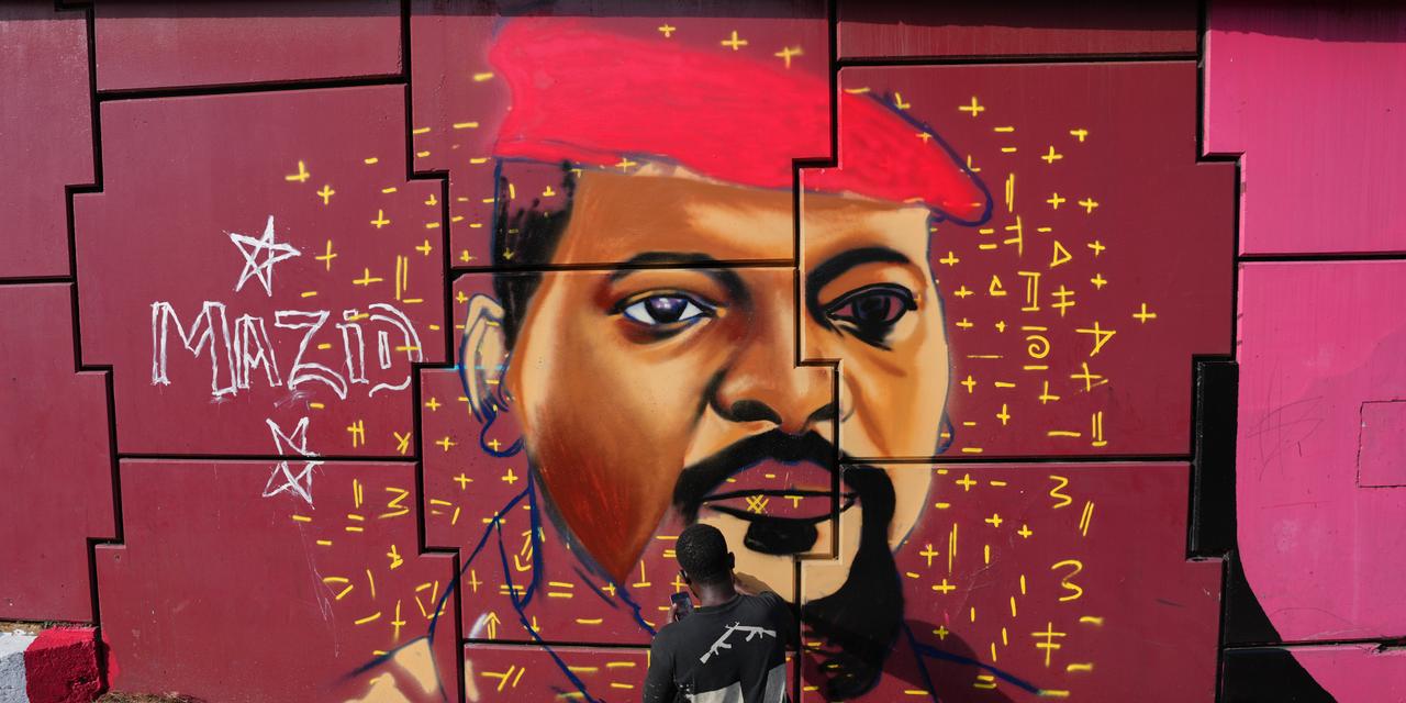 Graffiti artist Omar Diaw works on a mural depicting Guinea's President Mamadi Doumbouya on a street wall in Conakry, Guinea, Saturday, Sep. 20, 2025. (AP Photo/Misper Apawu)