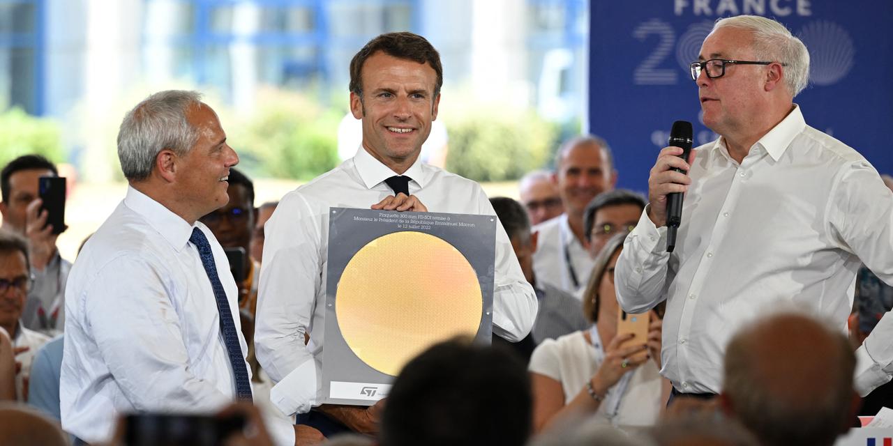 France's President Emmanuel Macron (C), flanked by Global Foundries chairman Thomas Caulfield (L), poses with a 300 mm silicon processed wafer as he listens to the speech of STM chairman Jean-Marc Chery (R) during a visit at STMicroelectronics in Isere region to unveil the strategy and investments for electronics within the framework of France 2030 in Crolles, southeastern France, on July 12, 2022. Emmanuel Macron announced on July 11, 2022 €5.7 billion investment by Franco-Italian STMicroelectronics and American GlobalFoundries to build a semiconductor plant in Crolles, near Grenoble. (Photo by Jean-Philippe KSIAZEK / POOL / AFP)