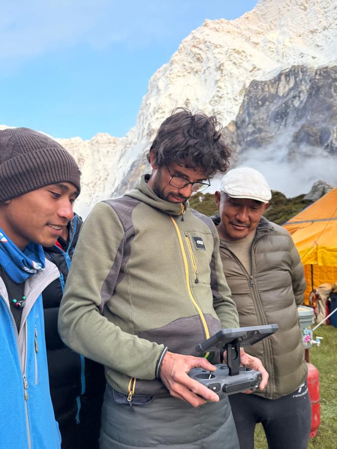 Le droniste Thibaut Marot (au centre), avec Tendi Sherpa (droite) et Tshering Sherpa, au camp de base de l’ascension de la face nord du Jannu Est, au Népal, le 4&nbsp;octobre&nbsp;2025.