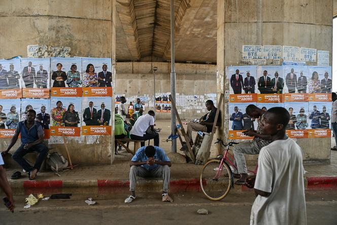 Des habitants se tiennent près d’affiches des candidats du Rassemblement des houphouëtistes pour la démocratie et la paix aux élections législatives de la commune d’Abobo, à Abidjan, le 20 décembre 2025.