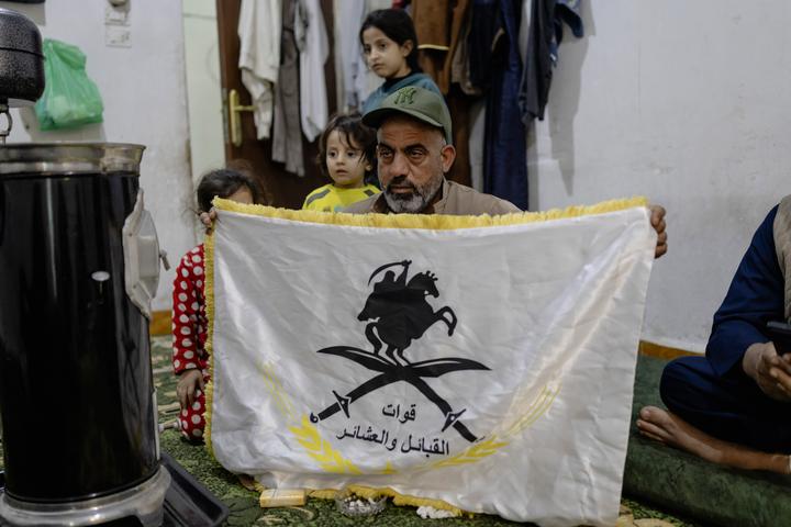 Weiss Al-Weiss, 43 ans, issu de la tribu Al-Agaidat et chef de la brigade Albu Kheir (dont il tient le drapeau) au sein de l’Armée des tribus. Le 5 décembre 2025 à Deir ez-Zor.