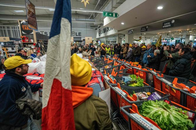 Des membres de la Confédération rurale (CR) et de la Confédération paysanne remplissent des chariots de produits importés lors d’une action visant à dénoncer l’importation de produits étrangers dans un supermarché de Carcassonne, le 30 décembre 2025. 