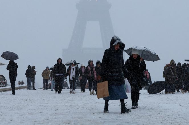 Des gens marchent place du Trocadéro près de la tour Eiffel, à Paris, alors qu’un temps hivernal, avec de la neige et des températures basses, touche une grande partie de la France, le 5 janvier 2026.