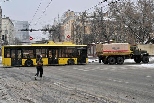 Un camion remorque un trolleybus en raison d’une panne d’électricité, à Kiev, le 9 janvier 2026.