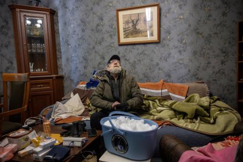 Serhi Prjistovski, devant un seau de neige qu’il compte faire fondre pendant la nuit, dans son appartement privé d’eau à la suite d’une frappe de drone russe la nuit dernière, à Kiev, le 10 janvier 2026.