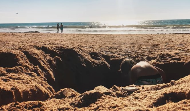 Enfant creusant un trou dans le sable sur une plage.