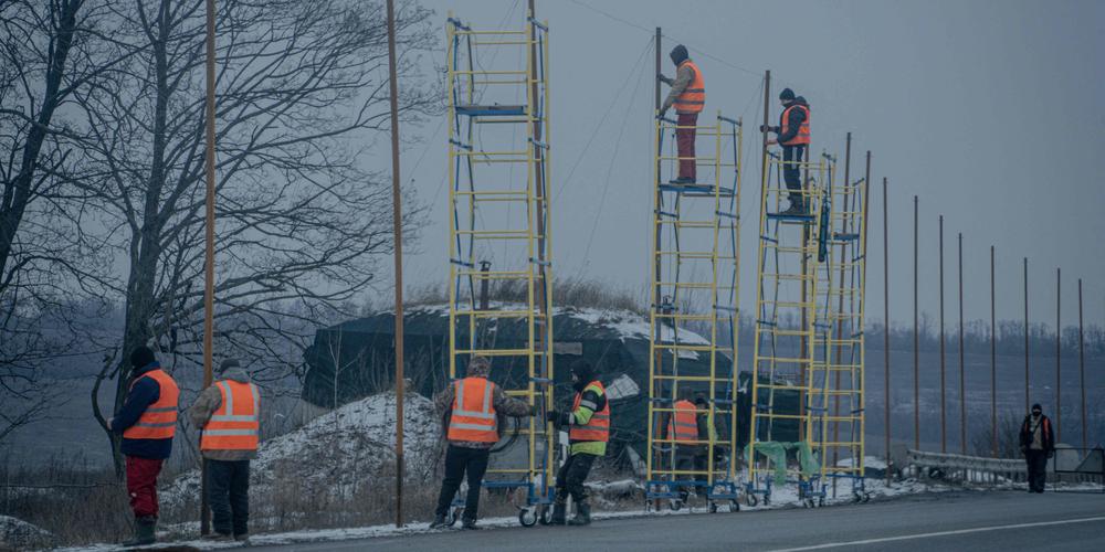 Des agents municipaux installent un filet antidrone sur la rocade de Kharkiv, le 10 janvier 2026. - IVAN SAMOILOV / AFP